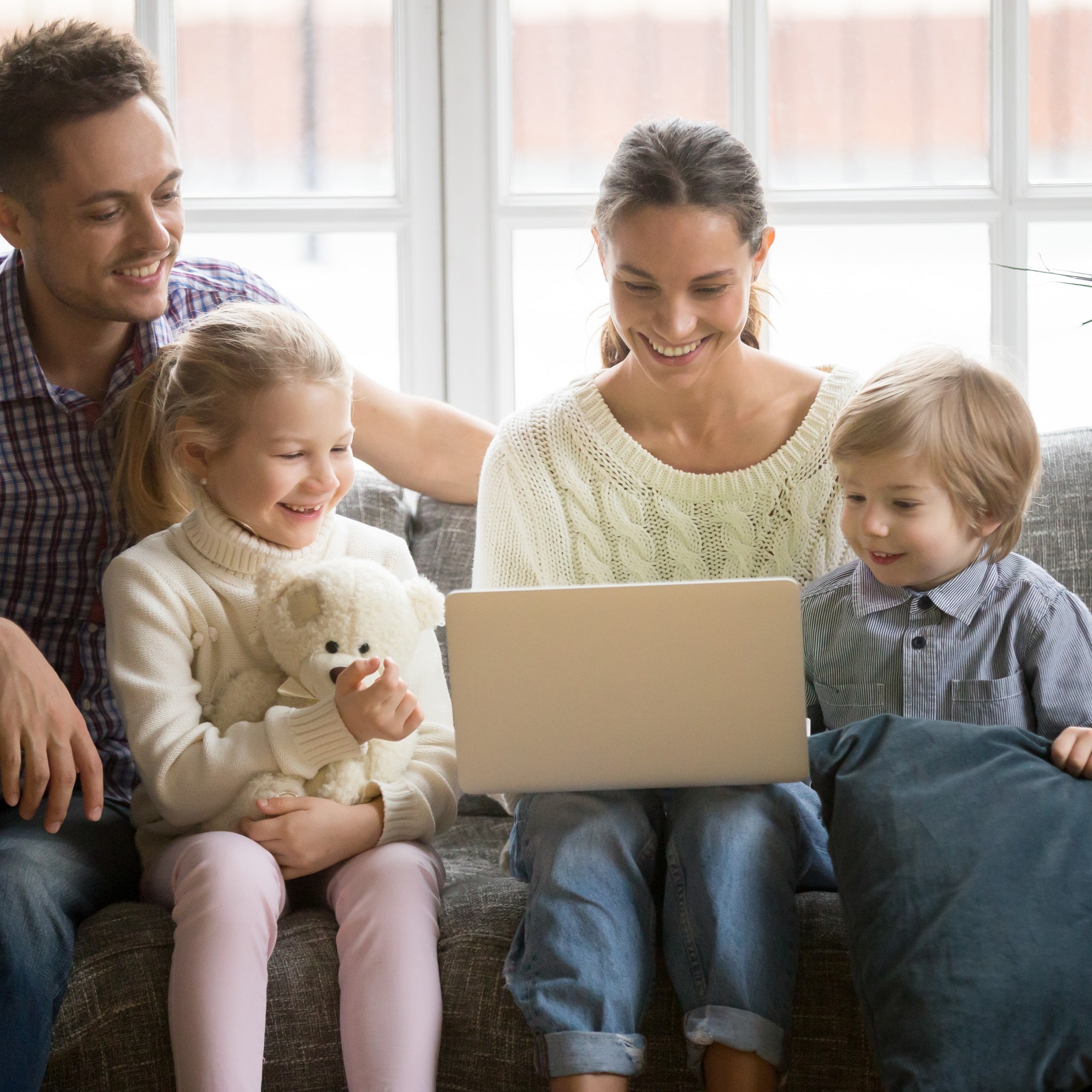 Happy family with children having fun using laptop on sofa